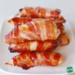 Bacon covered chicken nuggets sitting on a plate