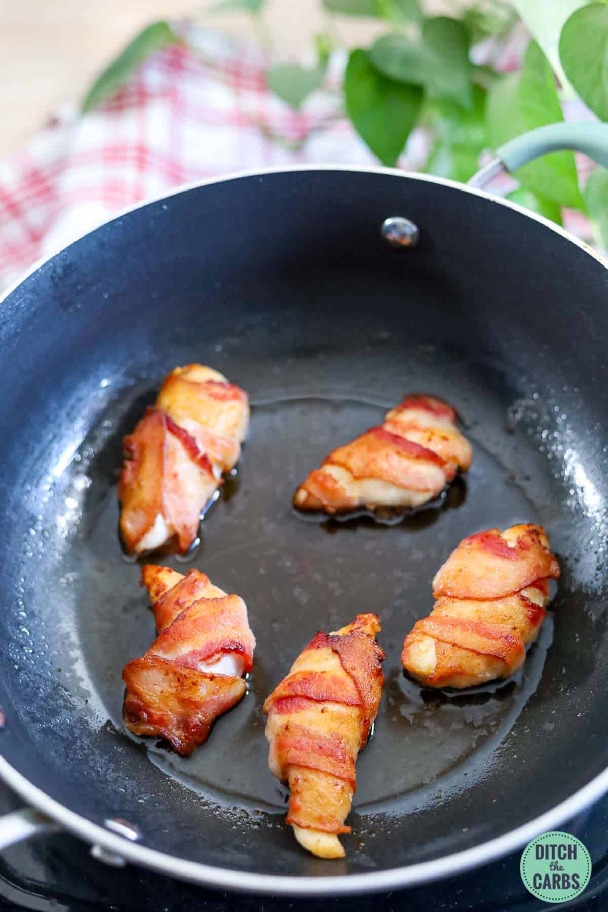 keto bacon wrapped chicken nuggets in a frying pan