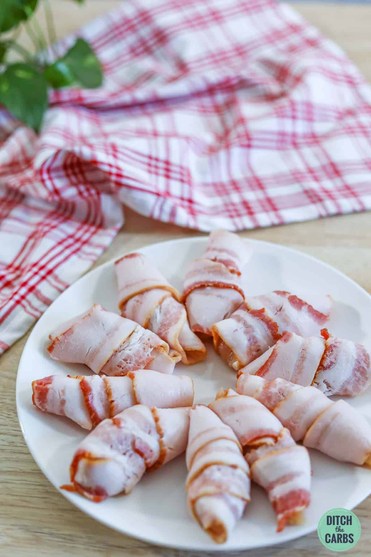 keto bacon wrapped chicken nuggets raw and on a white plate