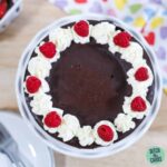 keto chocolate cake decorated with whipped cream and berries
