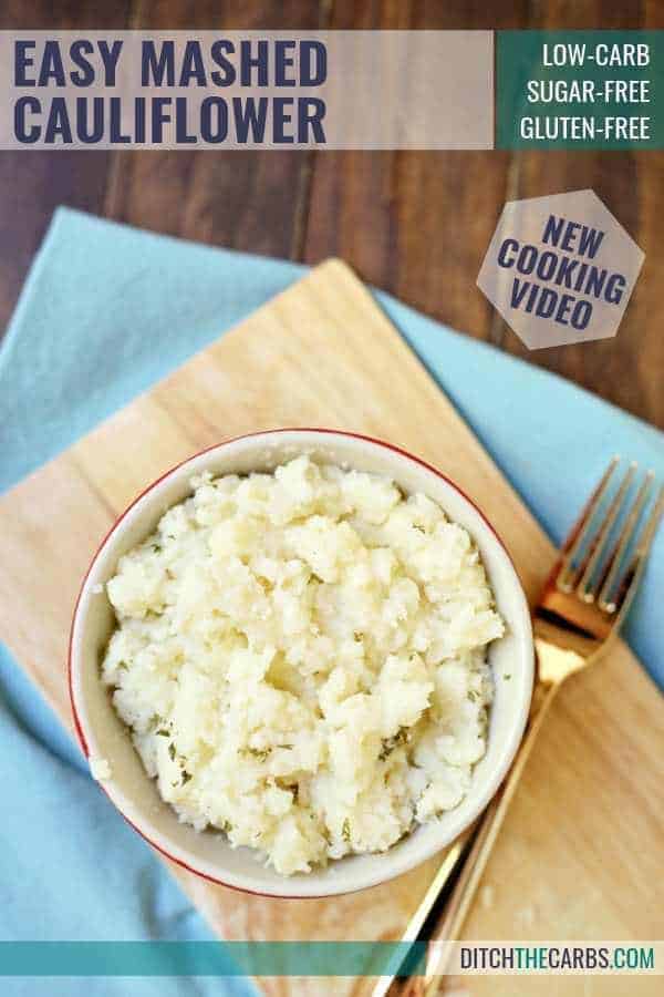 Mashed cauliflower on a wooden board and gold fork