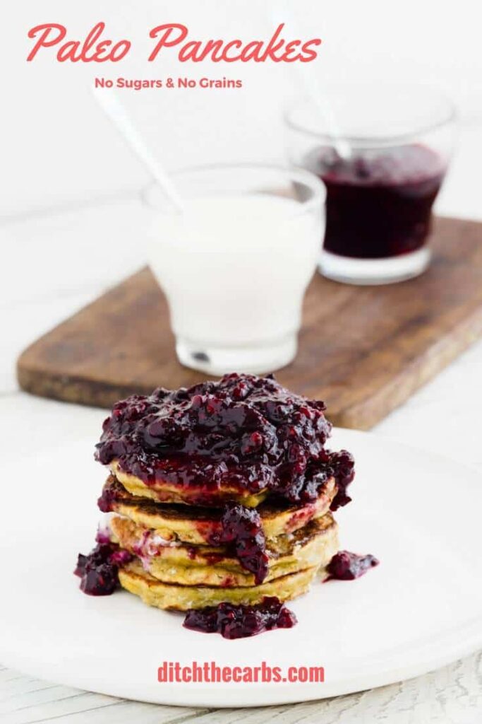 Paleo pancakes stepped on a table with coconut cream and fresh berry sauce