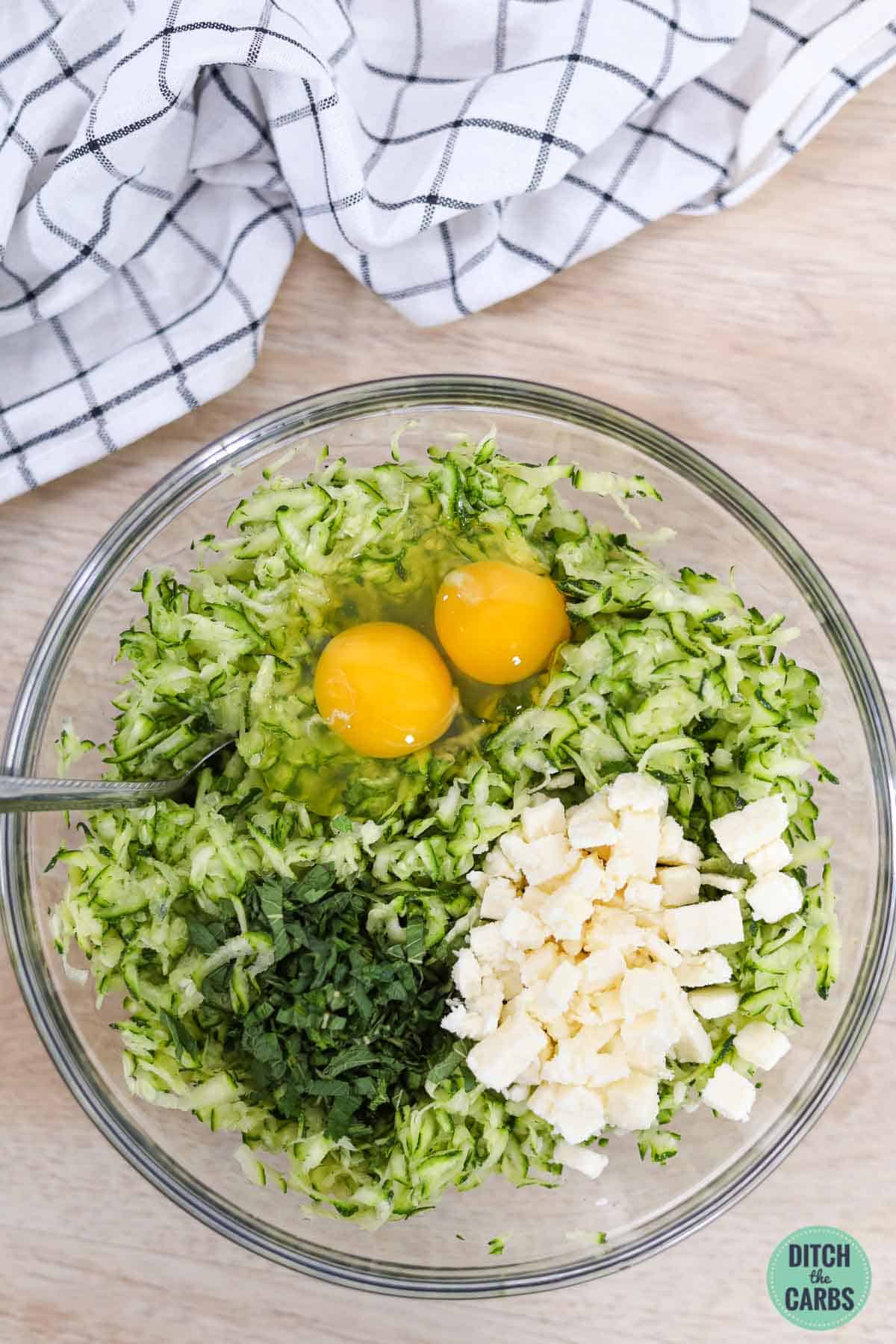 a mixing bowl with zucchini eggs and cheese