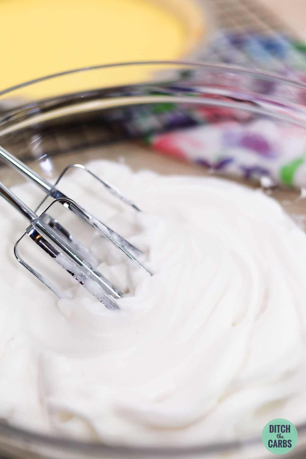whipped egg whites in a mixing bowl with electric beater