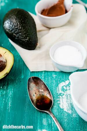 The ingredients for the sugarfree chocolate avocado mousse sitting on a blue table