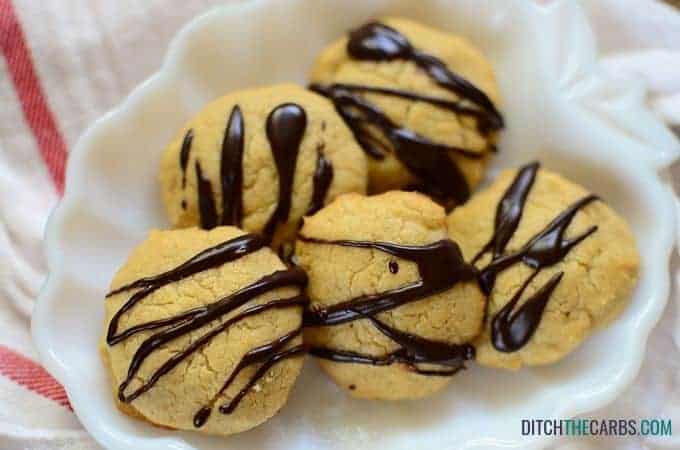Peanut butter cookies drizzled with dark sugar-free chocolate on a white plate