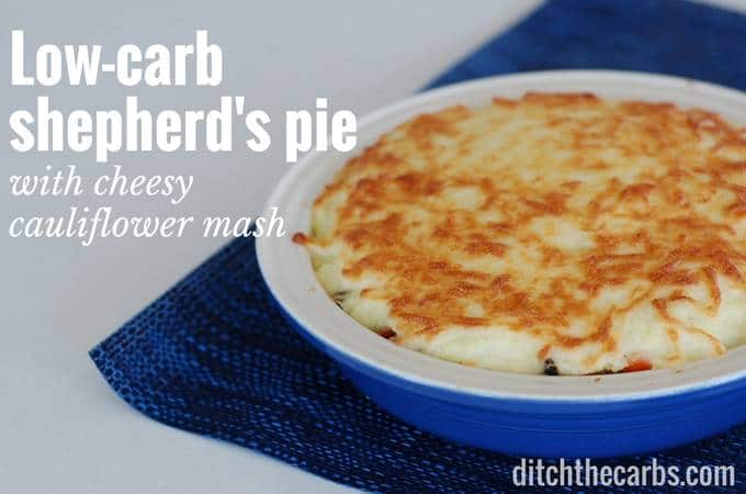Low-carb shepherd's pie with a cheesy cauliflower crust in a blue dish