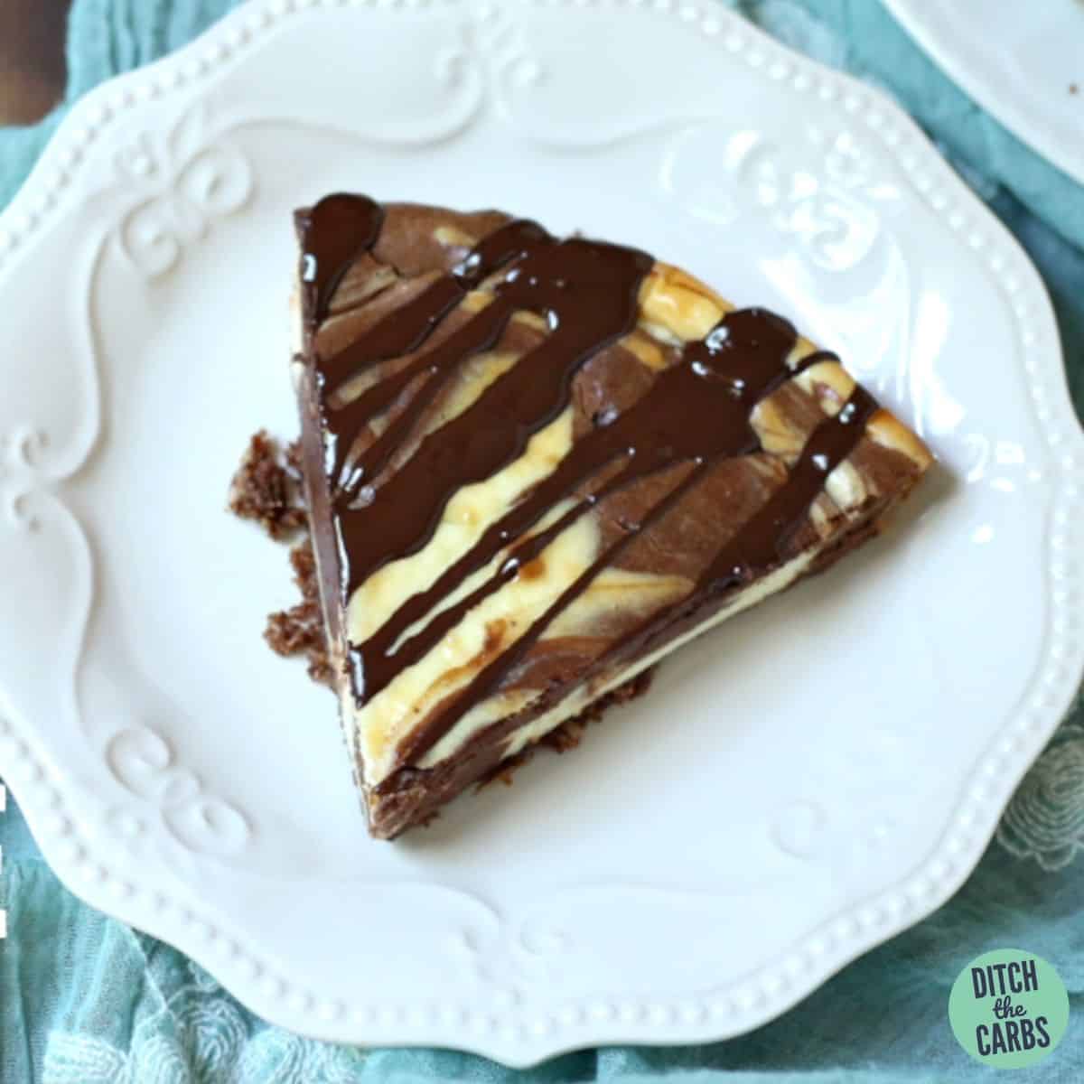 A slice of low carb chocolate swirl baked cheese cake drizzled with chocolate sauce on a plate