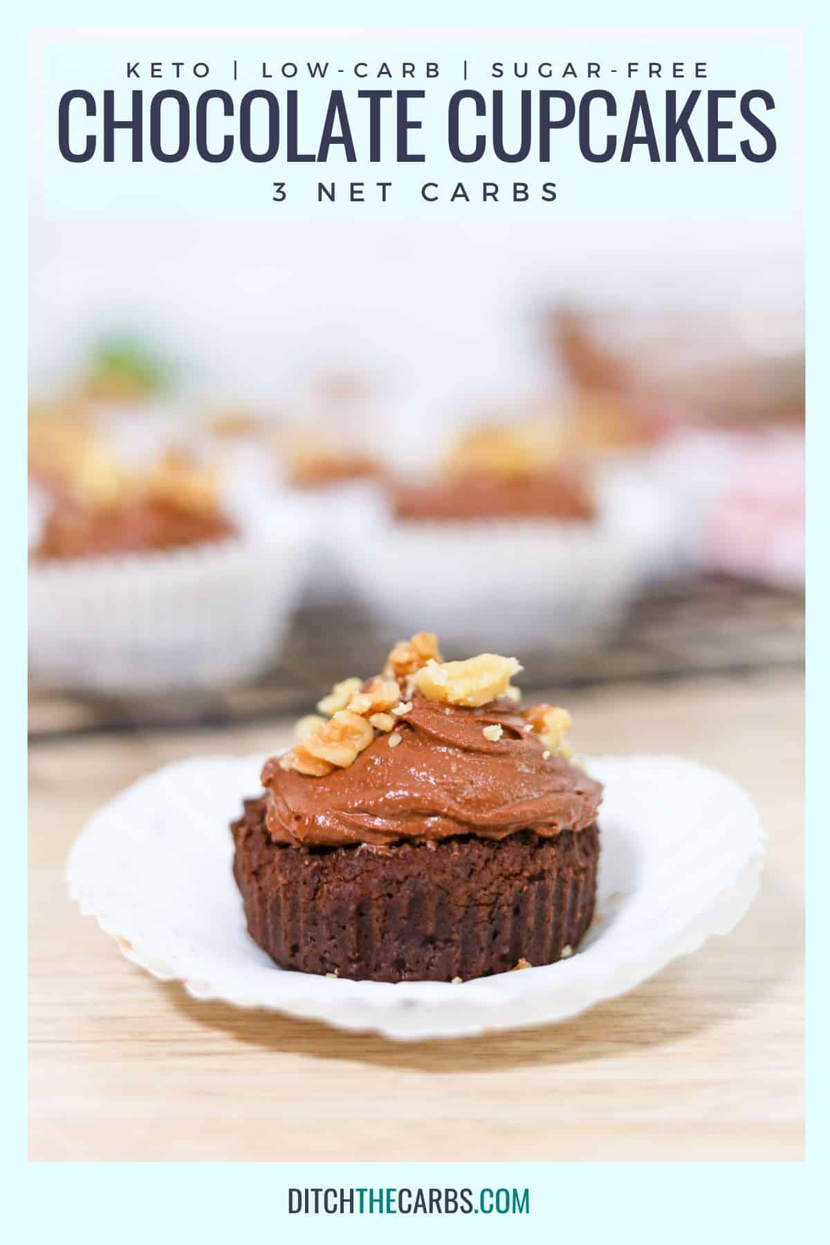 a chocolate cupcake covered in chocolate frosting wth a walnut on top
