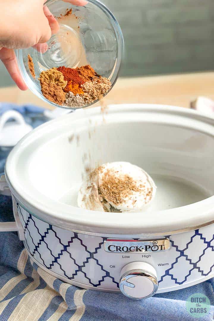 adding spices to coconut cream to the slow cooker