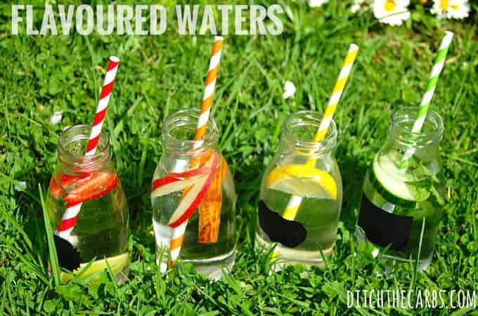 Four drink bottles with coloured straws and fresh fruit inside