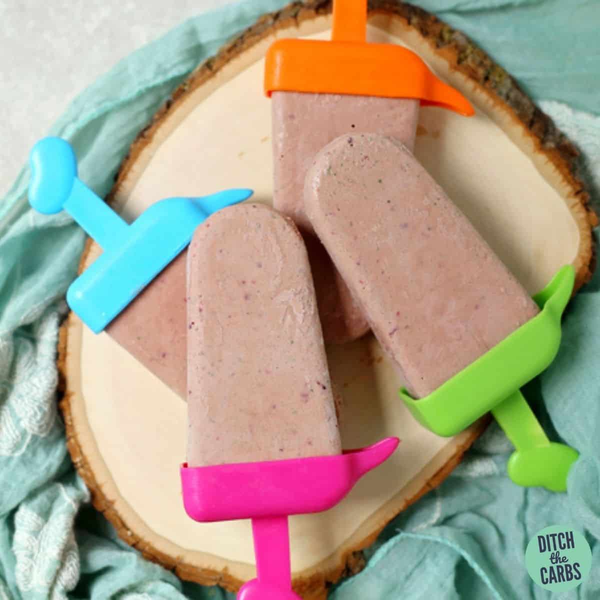 creamy keto berry popsicles sitting on a wooden platter