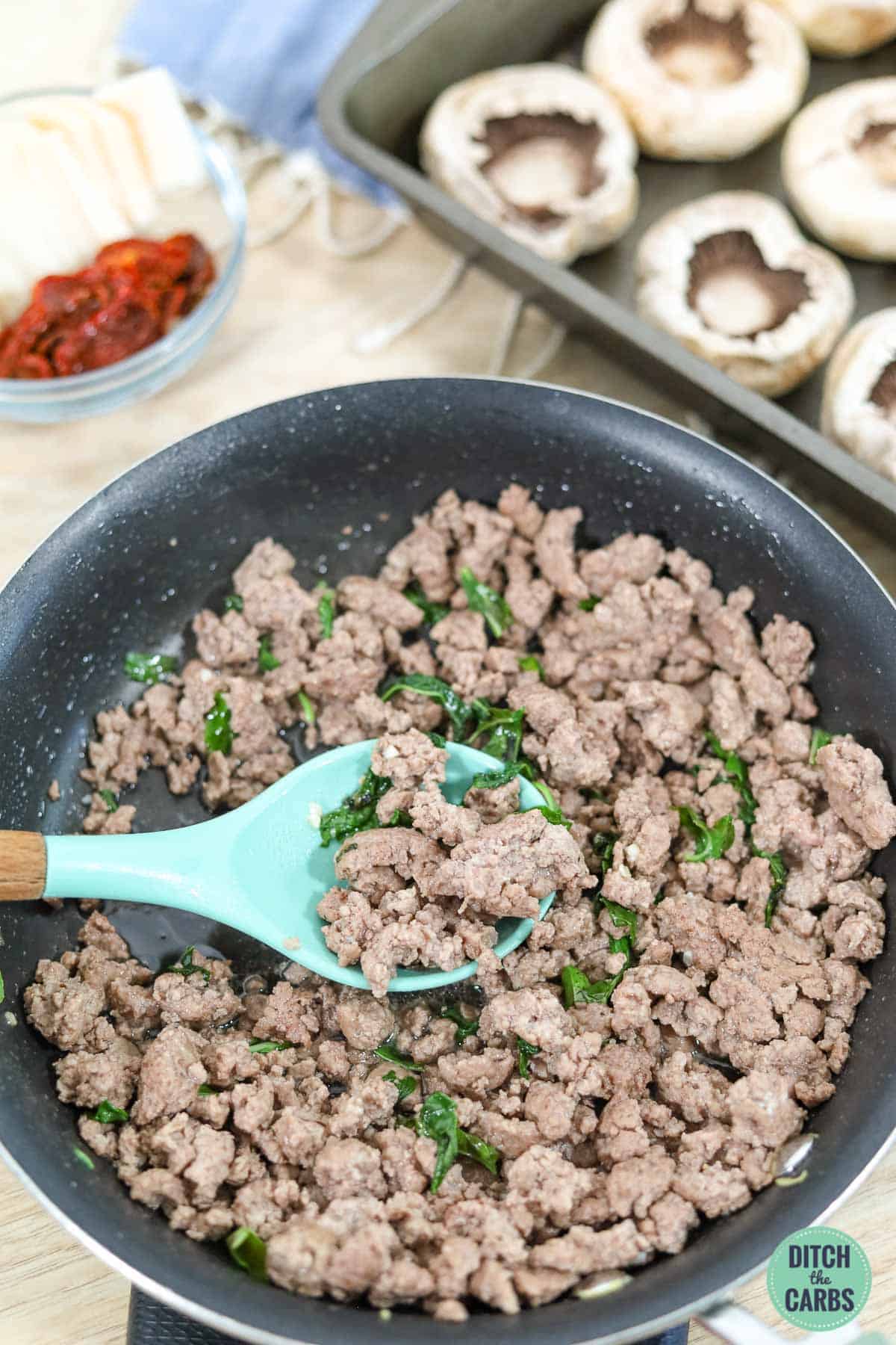 ground beef in a skillet with wooden spoon