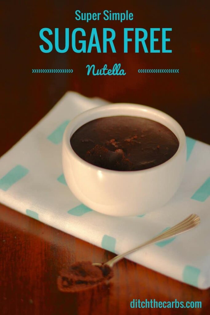 A white dish with sugar free nutella on a blue cloth and dark wooden table