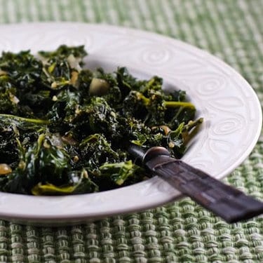 A bowl of sauteed kale in a white bowl