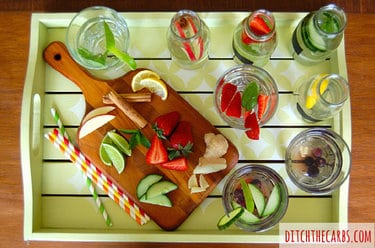 Selection of flavored waters and coloured straws on a wooden serving tray
