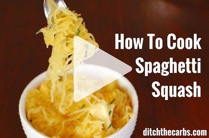 The fork lifting cooked spaghetti squash from a white serving dish with melted butter and herbs