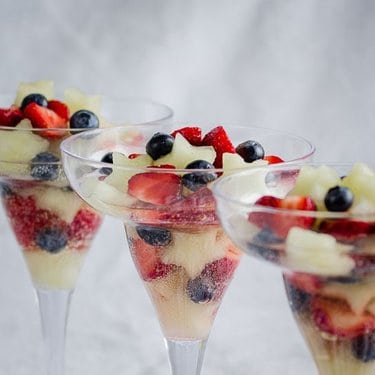 A close up of wine glasses with fruit and whipped cream