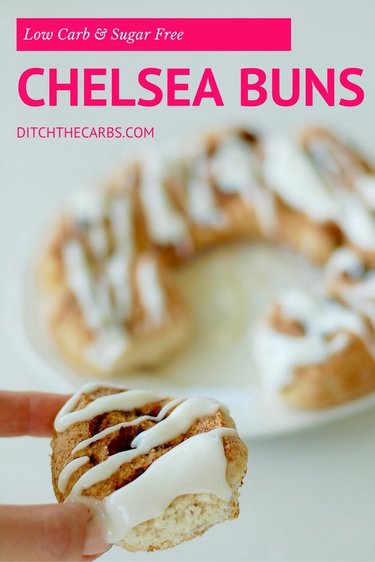 A hand holding one low-carb cinnamon bun drizzled with sugar-free frosting