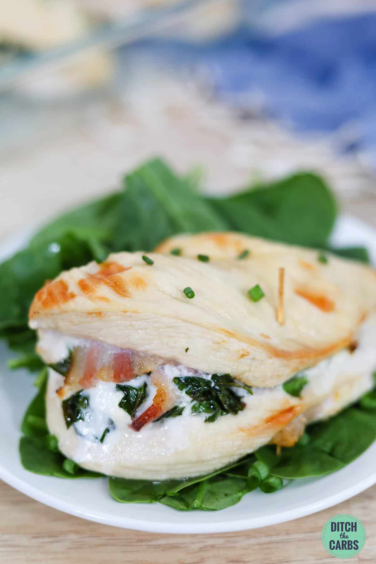 a baked cream cheese keto stuffed chicken breast on a plate and spinach salad