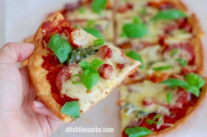 Keto meatlovers pizza held by a hand