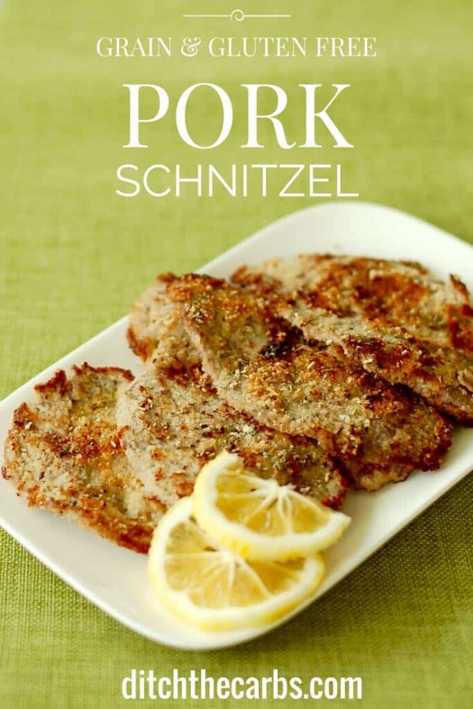 A plate of almond-crusted pork schnitzel with a garnish of sliced lemons