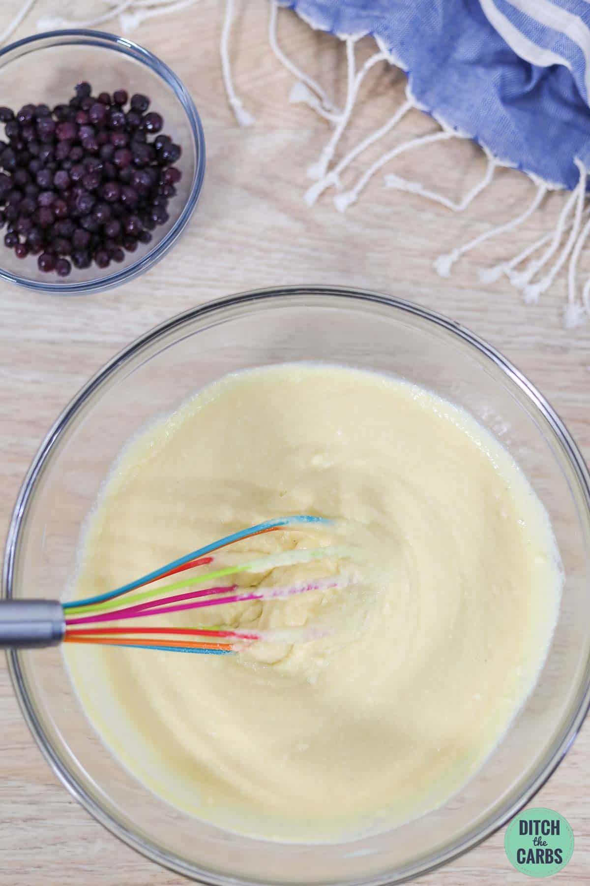 a bowl of pancake batter with a coloured whisk