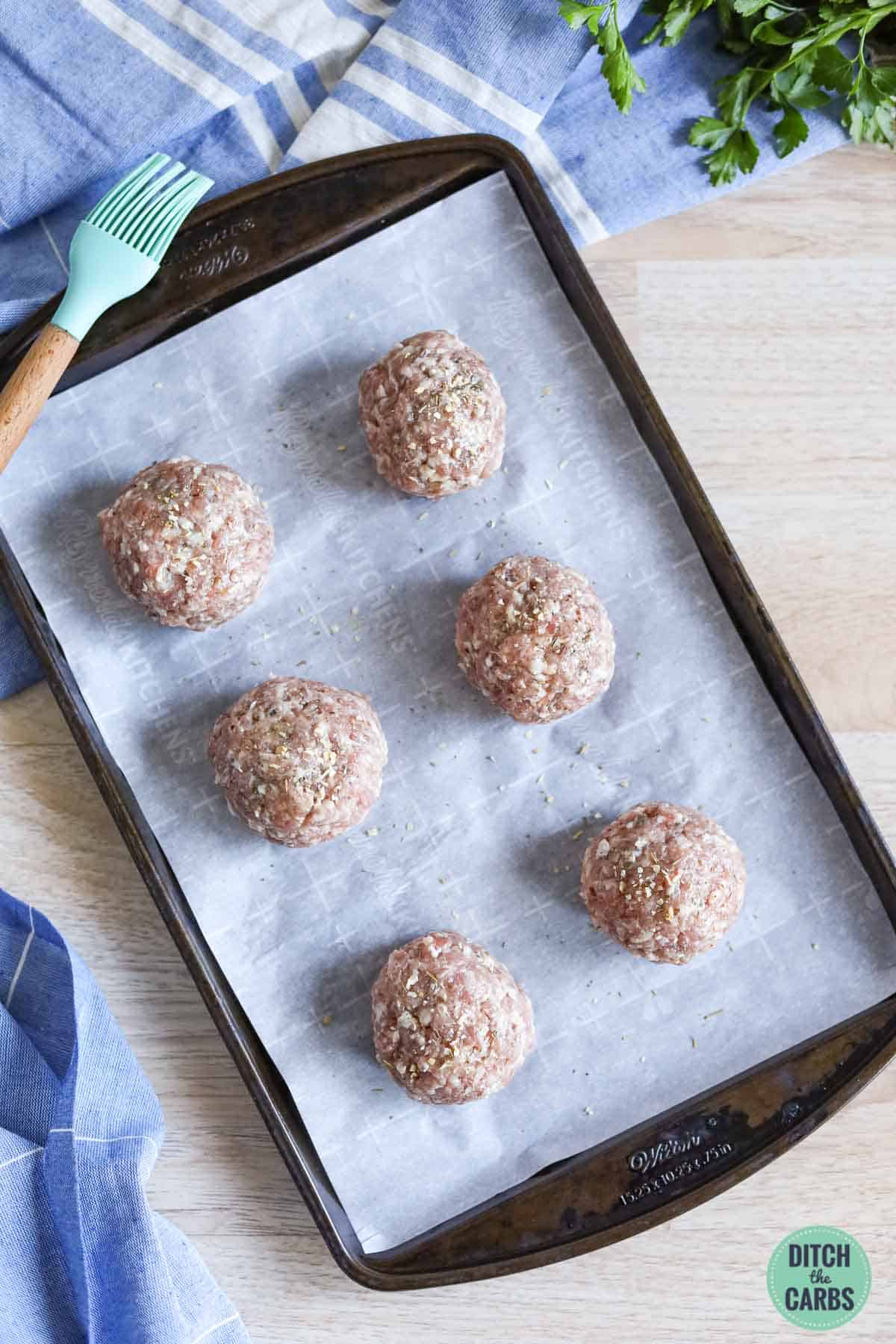 scotch eggs wrapped in ground pork on a baking tray
