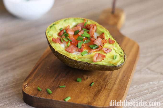 A slice of avocado sitting on top of a wooden cutting board 