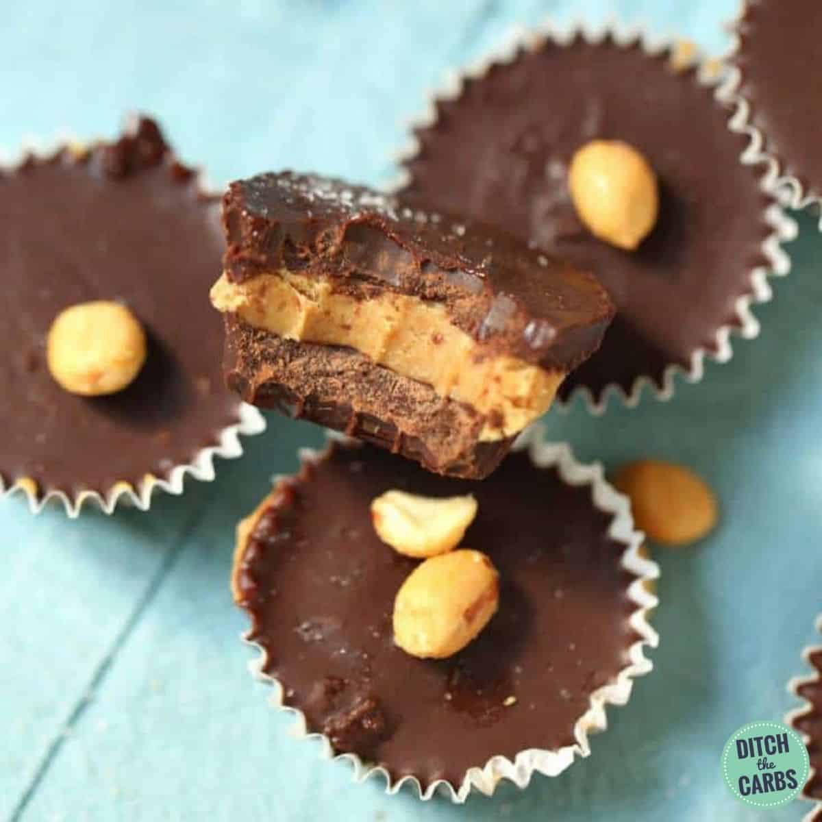 Sugar free and low carb peanut butter cups on a blue cloth with peanuts and salt