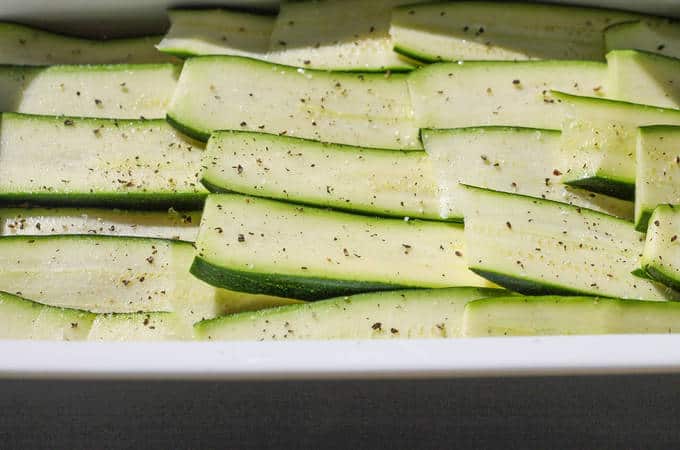 Slices of courgette salt pepper in a baking dish