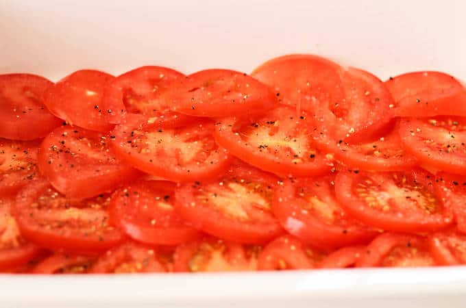 A close up of food, with tomato and courgette in a baking dish