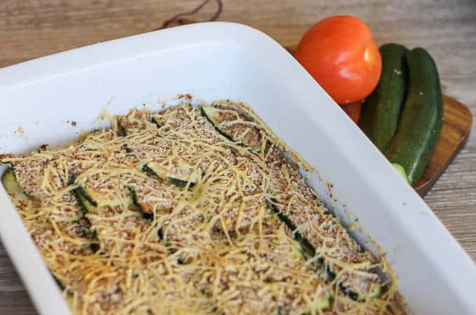 A dish is filled with food, with sliced courgette and shredded cheese after baking