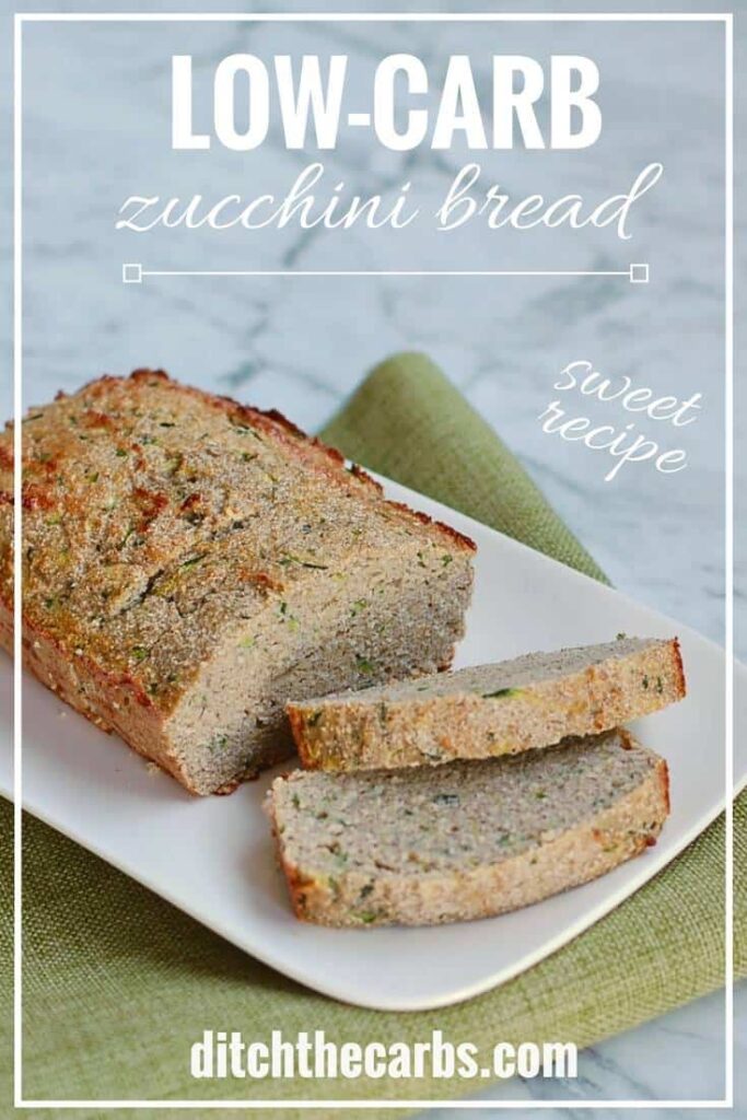 A loaf of low carb zucchini bread sliced on a white plate and sitting on a green cloth
