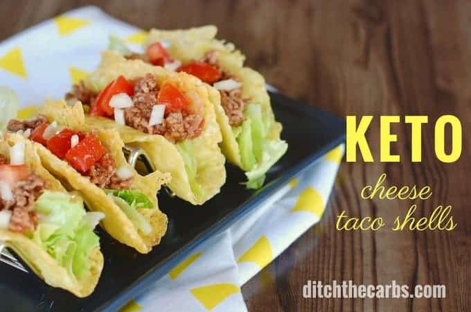 Cheese taco shells with lettuce and ground beef on a black tray