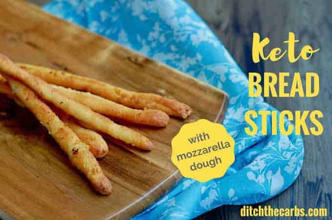 keto cheese breadsticks sitting on a wooden board and blue cloth