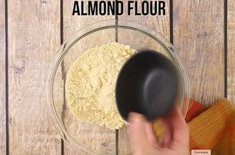 Hands adding almond flour to the pizza dough