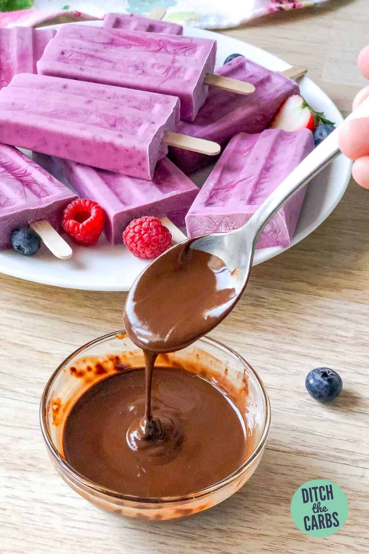melted chocolate being drizzled over frozen keto popsicles