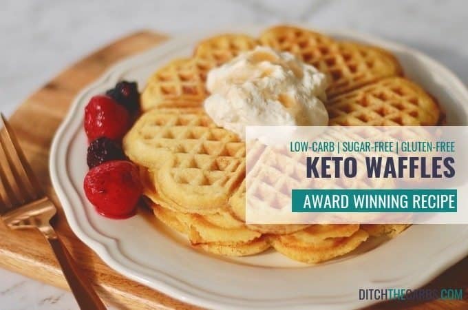 keto waffles stacked on a plate with whipped cream and berries