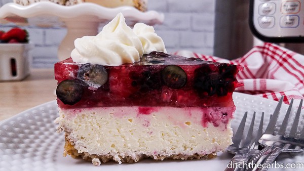 A piece of cheesecake with berry jello and fresh berries
