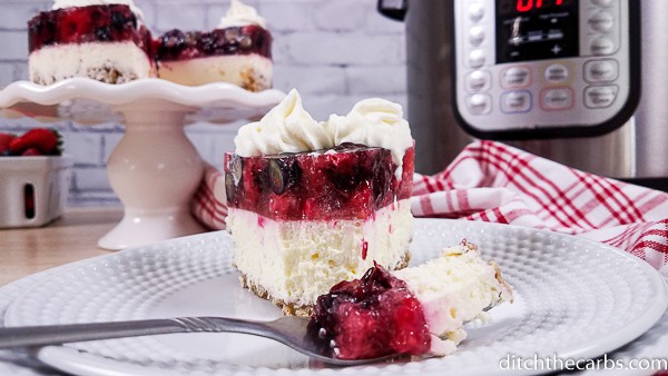 sliced berry cheesecake sitting in front of an Instant Pot with a fork