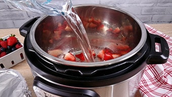 Pouring hot water onto the fresh berries in the Instant Pot 