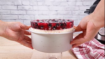 Removing the Instant Pot cooked berry cheesecake from the cake tin using a glass on the kitchen bench