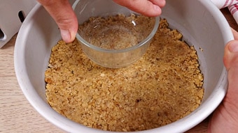Pressing the cheesecake crust with a glass bowl into the baking tin