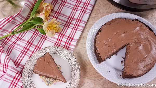 low-carb Instant Pot chocolate cake served and sliced on a plate with flowers to the side