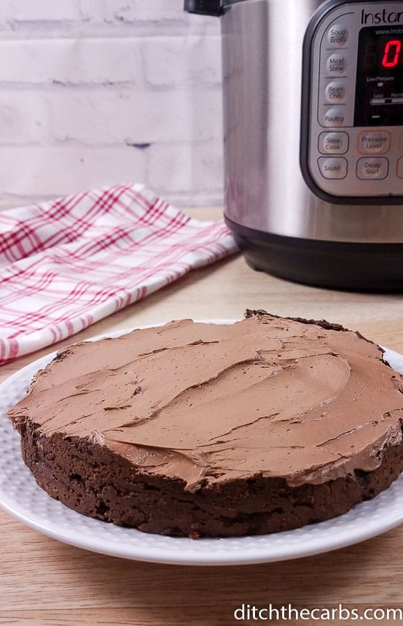 Low-carb Instant Pot chocolate cake sliced and served about to be cut with the Instant Pot in the background