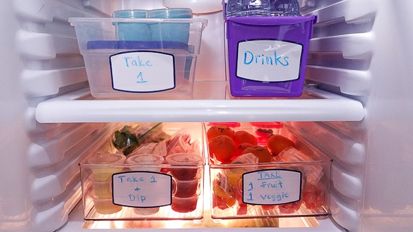 An open refrigerator filled with healthy lunchbox meal prep boxes