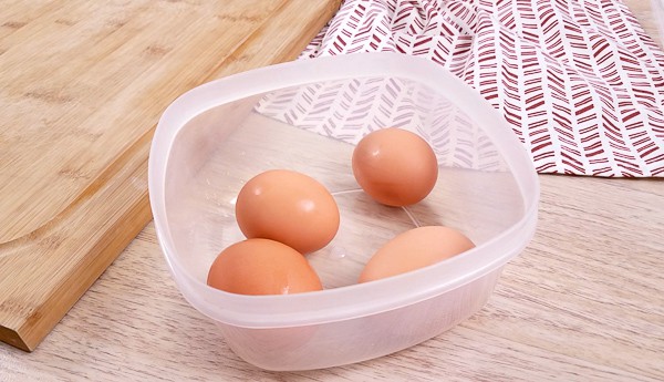 Boiled eggs in a lunchbox on a bread board