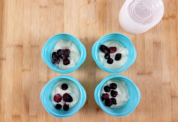 Yoghurt and fresh berries in 4 blue lunchbox pots