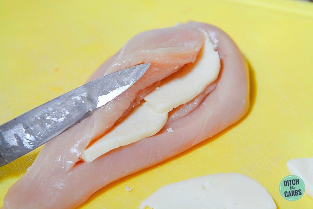 raw chicken breast being stuffed with cheese